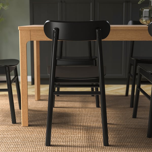 Trois chaises RÖNNINGE noires autour d’une table en bois, montrant un design robuste et un confort avec un grain de bois visible.