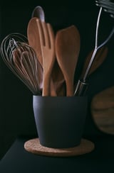 Porte-ustensiles RÖRT noir avec outils en bois, fouet en fil, base solide.