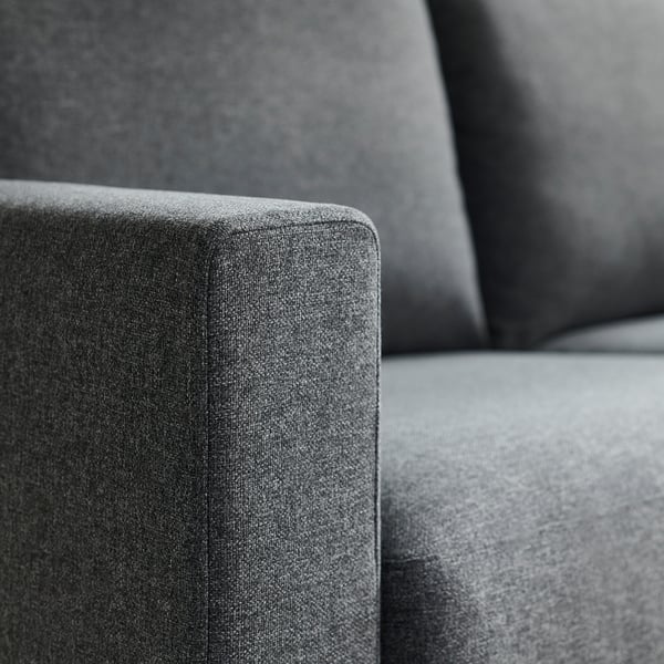 Gros plan d’un canapé moderne en tissu gris, mettant en valeur son design élégant, sa texture lisse et ses coussins de soutien.