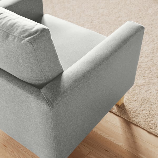 Fauteuil moderne en tissu gris sur un sol en bois. Style confortable, rembourré avec un détail de coussin dorsier.