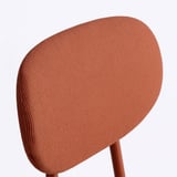 Gros plan du dossier d’une chaise rembourrée dans un tissu texturé, mettant en valeur son design et sa qualité.