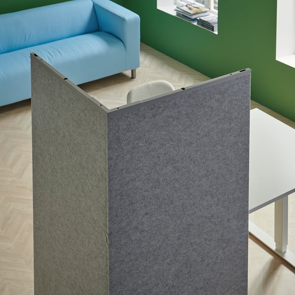 Bureau moderne avec séparateur gris, canapé bleu, table blanche et chaise grise.