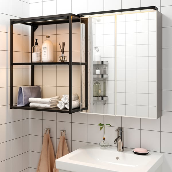 Salle de bain moderne avec étagère éclairée, miroir, lavabo, serviettes et articles de toilette.