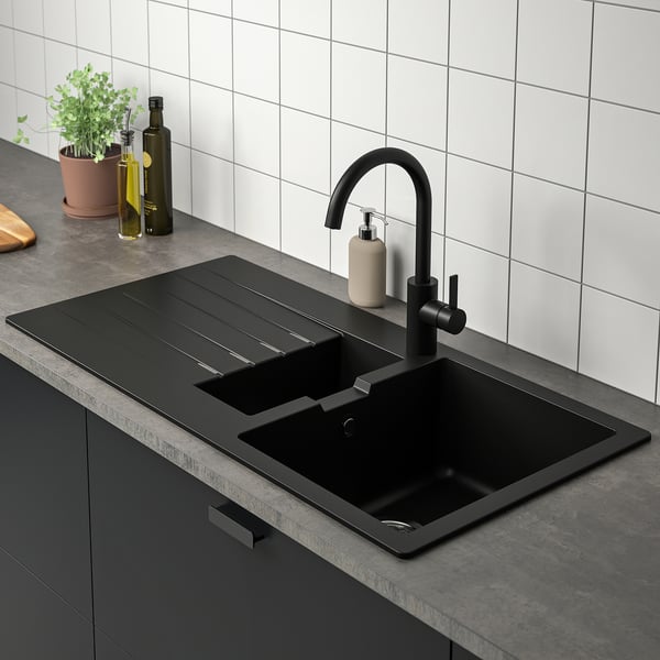 Évier de cuisine moderne avec robinet noir et égouttoir réversible.