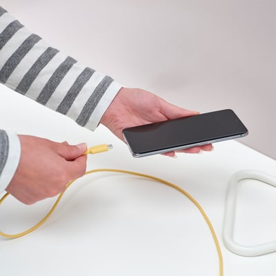 Personne branchant un câble USB-C jaune. Flexible, durable et empêche la surchauffe.
