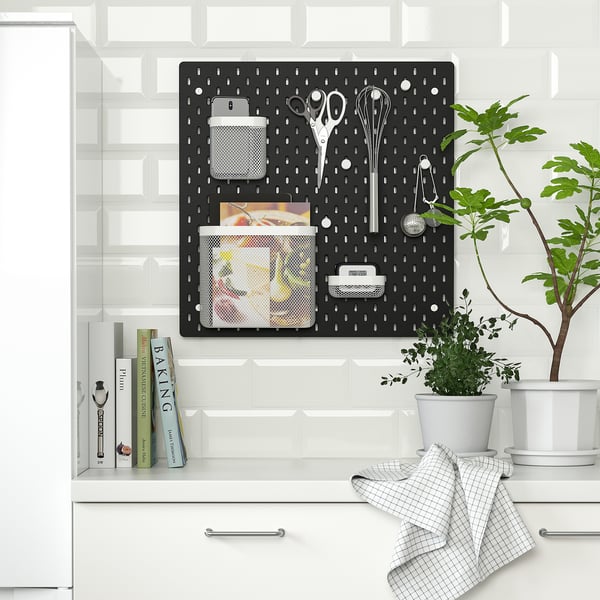 Panneau perforé SKÅDIS dans la cuisine avec smartphone, ciseaux, fouet, clés, magazines et serviette.