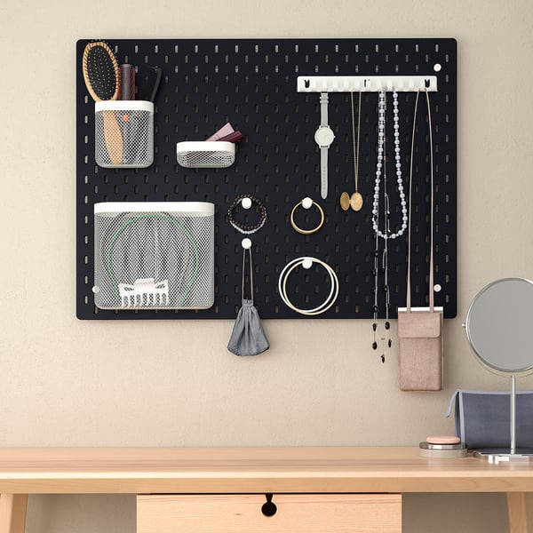 Panneau perforé noir SKÅDIS avec pochettes et accessoires, au-dessus d’un bureau en bois avec miroir