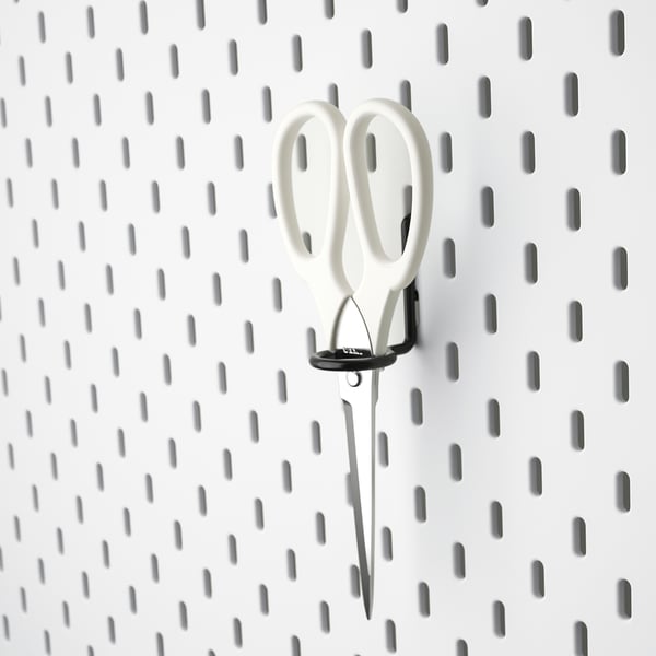 Des ciseaux blancs sont suspendus sur un panneau perforé SKÅDIS noir pour le rangement.