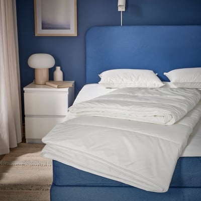 Couette SKOGSFRÄKEN blanche sur lit moderne avec literie bleue.