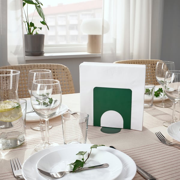Table à manger avec verres, assiettes et porte-serviettes, décorée de nappes et de plantes.