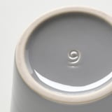 Gros plan d’une base de pots en grès gris, lisse et émaillée, montrant la qualité de l’artisanat.