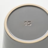 Jardinière cylindrique grise avec bord doré, montrant 15 sur la base, indiquant la qualité et le design.