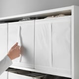 Une personne tient un organisateur de rangement SKUBB blanc. Il dispose de plusieurs compartiments pour un rangement bien rangé, conçu pour une armoire de 100 cm de large.