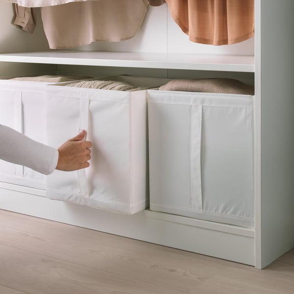 Personne sortant la boîte de rangement SKUBB blanche de l’armoire, présentant la poignée et le design compact.