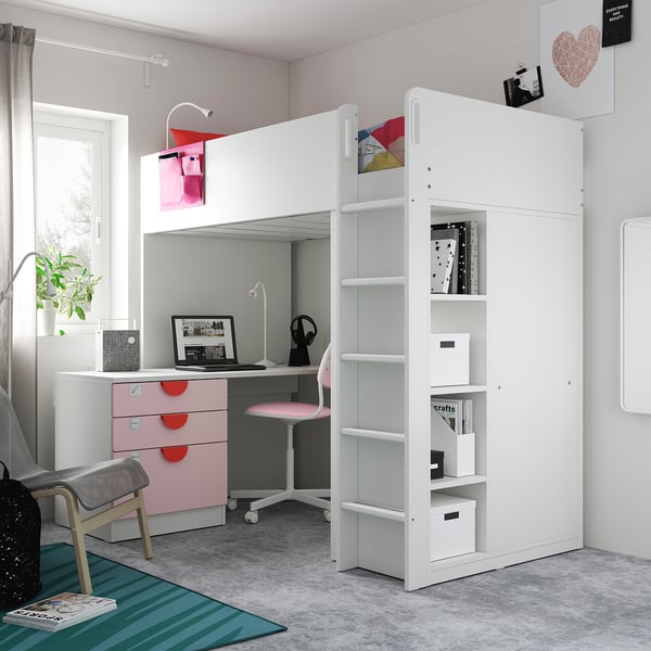 Un lit mezzanine SMÅSTAD avec un bureau, une armoire et des étagères blanches, avec des accents roses. Il est compact, parfait pour les petits espaces.