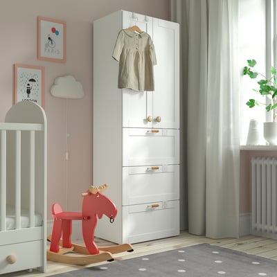 Chambre d’enfant confortable avec armoire SMÅSTAD blanche, cheval à bascule rouge, berceau et tapis à pois.