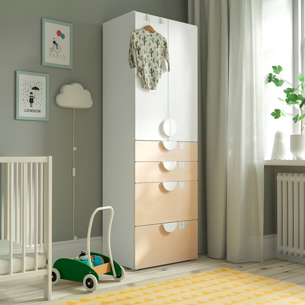Chambre de bébé moderne avec armoire SMÅSTAD dans les tons blancs et bois, voiture jouet verte, grenouillère suspendue et art encadré.