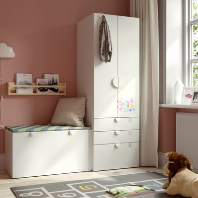 Chambre d’enfant avec armoire SMÅSTAD, banc, étagère à livres et tapis coloré.