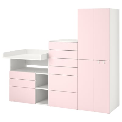 Un ensemble de rangement pour chambre d’enfant IKEA SMÅSTAD en rose clair avec plusieurs tiroirs et étagères, conçu pour les essentiels de bébé et se transformant en bureau.