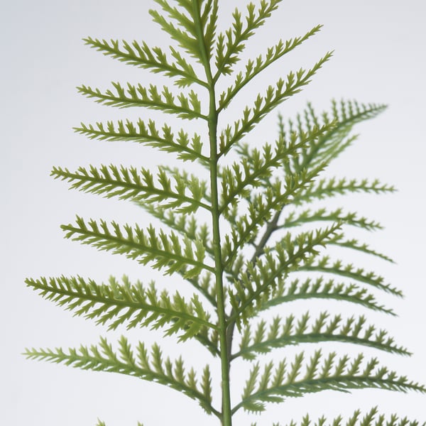 Gros plan de verdure artificielle de haute qualité, de feuilles vertes vifs et réalistes attachées à une tige réglable en fil d’acier.