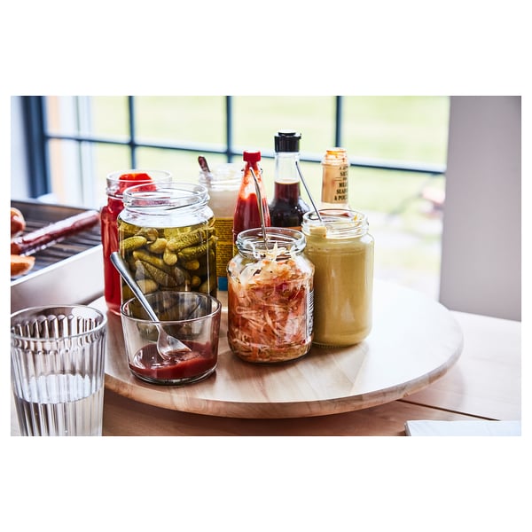 Plateau en bois SNUDDA, brun, rond, avec divers condiments et ustensiles de service dessus.