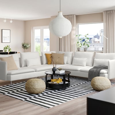 Salon confortable avec canapé SÖDERHAMN, grande fenêtre, tapis rayé, poufs, table basse, suspension et plantes.