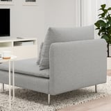 Canapé gris moderne sur tapis avec table basse et plante, télévision en arrière-plan.