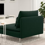 Canapé moderne vert foncé avec des assises profondes et des pieds en métal dans un salon minimaliste.