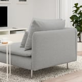 Un canapé moderne gris clair avec des coussins sur un tapis moucheté. Le canapé est conçu avec des pieds hauts et des assises profondes pour plus de confort.
