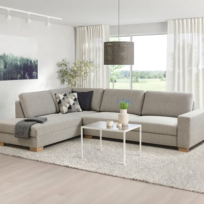 Salon minimaliste avec canapé en forme de L, table basse, grandes fenêtres, vue sur la nature.