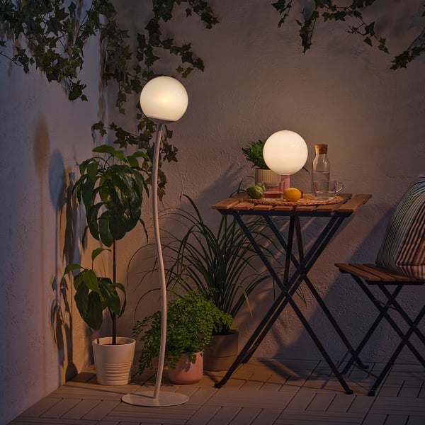 Petit patio extérieur avec des lampes globe, des plantes et une table pour deux.