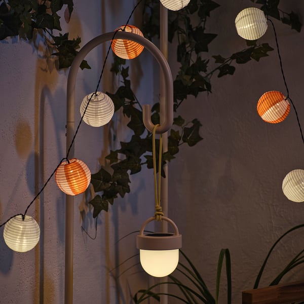 Les lanternes à énergie solaire émettent une lumière nocturne chaude, se rechargeant le jour et s’activant automatiquement dans l’obscurité, fixées à un support métallique incurvé avec des plantes.