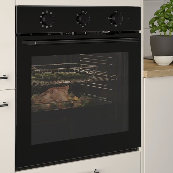 Four encastré noir avec cuisson des aliments à l’intérieur, avec répartition uniforme de la chaleur et fonction d’autonettoyage, installé dans une cuisine moderne.