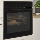 Four encastré noir avec cuisson des aliments à l’intérieur, avec répartition uniforme de la chaleur et fonction d’autonettoyage, installé dans une cuisine moderne.