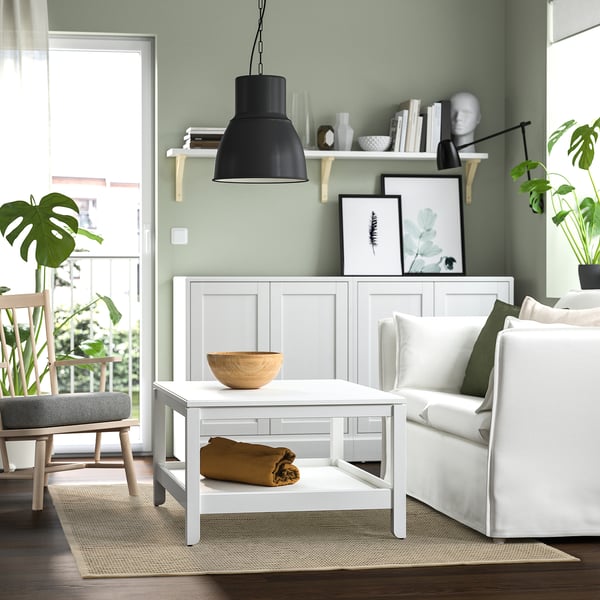 Salon moderne avec murs verts, canapé blanc, table basse et tapis rayé beige et noir, STARREKLINTE.