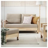 Un salon moderne avec un canapé beige, des oreillers, des meubles en bois, un tapis rayé et une lampe.