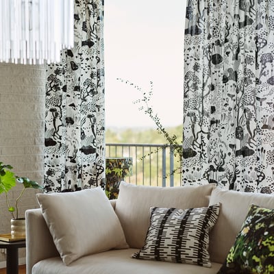 Salon moderne avec rideau de Stockholm et canapé beige, oreillers rayés et vue sur le patio.