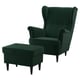 Ensemble chaise à oreilles et pouf en velours vert émeraude. Dos haut, bras roulés, jambes en bois foncé.