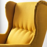 Chaise à oreilles jaune en gros plan, montrant un dossier haut, un siège capitonné et un design robuste, mettant en valeur l’artisanat et le confort.