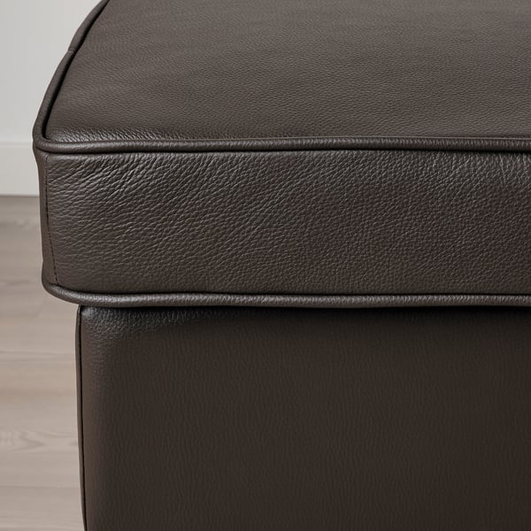 Ottoman ou repose-pieds en cuir noir, mettant en valeur un savoir-faire de haute qualité avec un matériau lisse et durable et des coutures soignées.