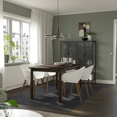 Salle à manger moderne avec table extensible STRANDTORP, chaises en bois sombre et blanches, murs verts et grande fenêtre.