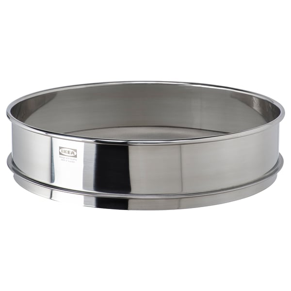 Un tamis rond en acier inoxydable ikea STRÖAD, utilisé pour la cuisson et la décoration, avec une finition réfléchissante.