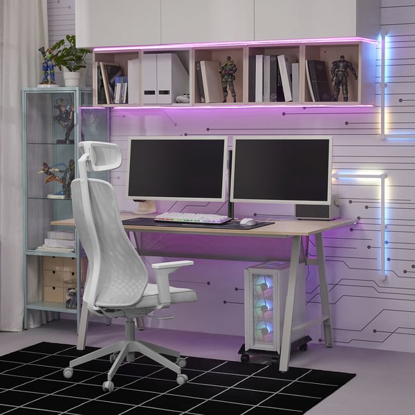 Configuration de bureau de jeu moderne avec deux moniteurs, chaise blanche et lumières LED violettes. Comprend des figurines, des plantes et des étagères organisées.