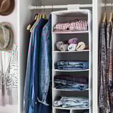 Placard organisé avec des vêtements bleus et des étagères de rangement suspendues blanches, faisant partie de la série STUK.