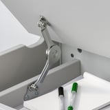 Un bureau pour enfants avec un dessus relevable et un espace de rangement, doté d’un support de couvercle réglable pour plus de sécurité.
