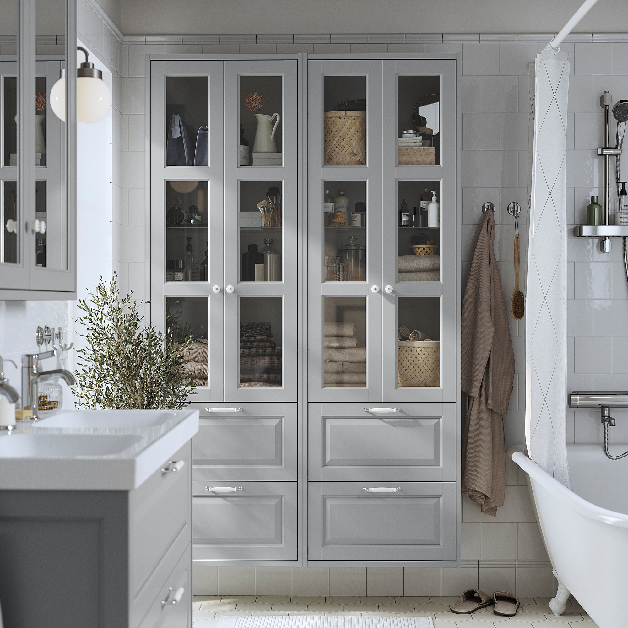Armoire TÄNNFORSEN grise avec portes et tiroirs en verre dans la salle de bains à côté de la baignoire et du lavabo.