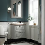 Configuration moderne de la salle de bain grise. Comprend une armoire murale, un évier, une toilette et un radiateur. Sol en damier.
