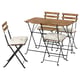 Ensemble de patio extérieur avec table en bois et 4 chaises. Les chaises ont des coussins blancs, des cadres en métal noir.