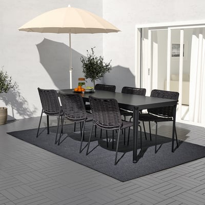 Ensemble table et chaises d’extérieur noir, avec parasol beige sur patio carrelé, idéal pour les petits rassemblements.