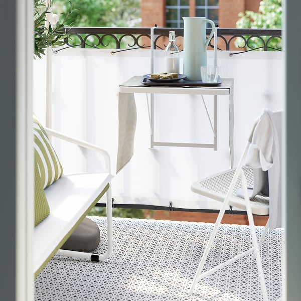 Un plateau blanc contient un pichet et des verres sur une table de balcon, idéal pour servir et installer la plupart des étagères à plateaux.